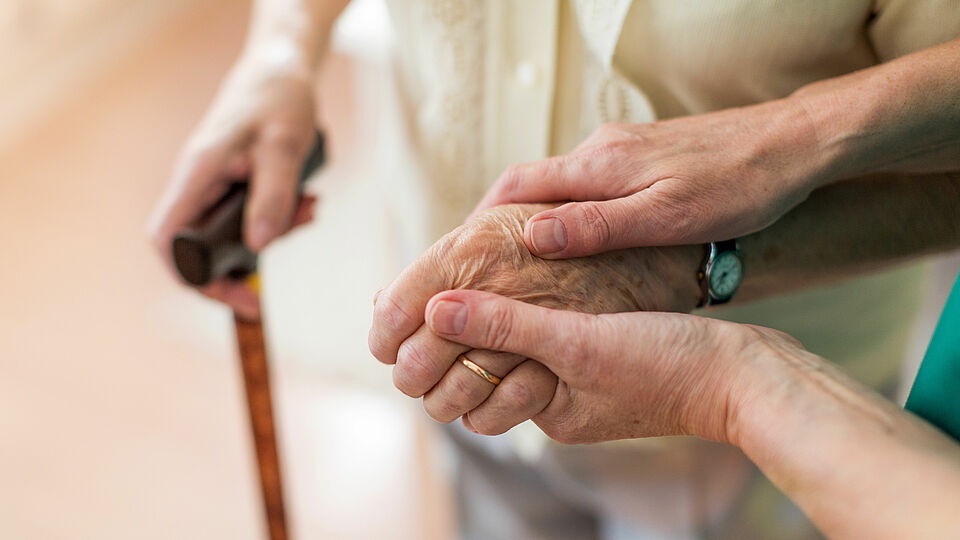 Hände von 4 Menschen sind zu sehen davon ist eine Hand am Gehstock und die anderen berühren sich