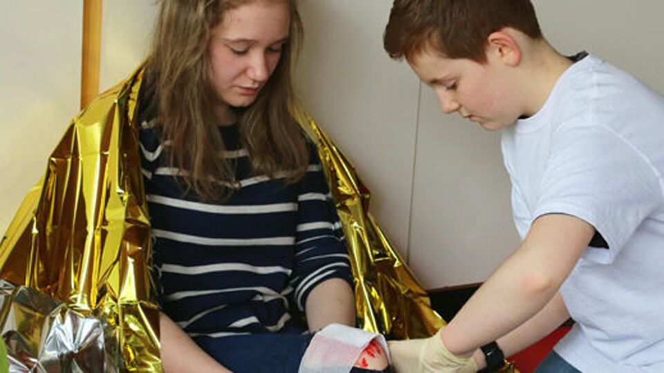 Ein Mädchen und ein Junge, das Mädchen hat eine Wärmedecke in gold umgelegt